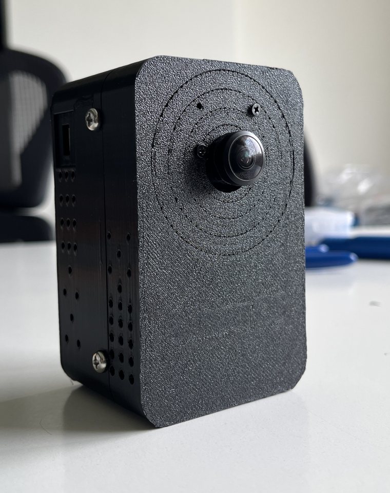 A finished AI camera unit in its black textured enclosure, wide-angle lens on the front